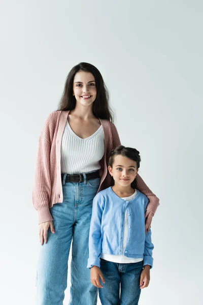 Young brunette woman with daughter smiling at camera isolated on grey - foto de stock