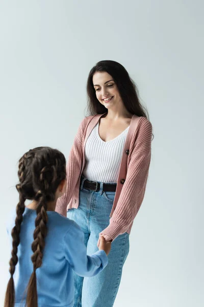 Happy brunette woman holding hands of daughter isolated on grey — стоковое фото