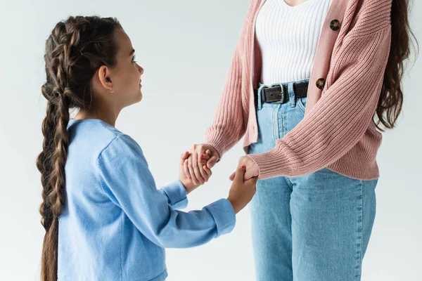 Girl with pigtails holding hands of mother in jeans isolated on grey — Stockfoto