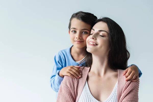 Brunette woman with closed eyes smiling near daughter looking at camera isolated on grey — Fotografia de Stock