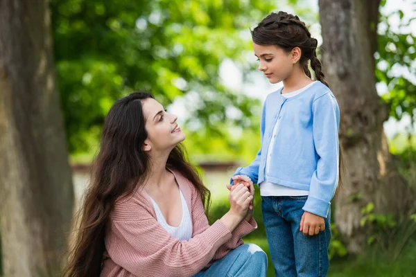 Joyful woman holding hand of daughter in park — Foto stock