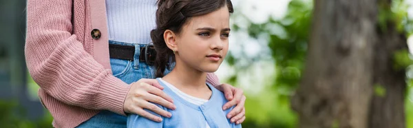 Tense girl looking away near mom hugging her shoulders, banner — Stockfoto