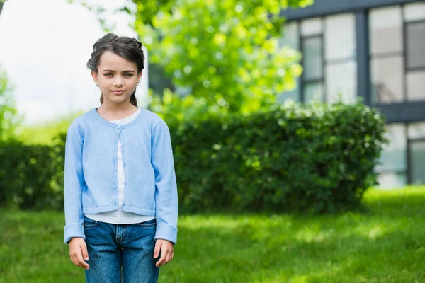 Serious ukrainian child in blue jumper and jeans looking at camera on blurred background — Photo de stock