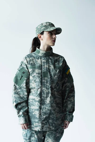 Military woman with ukrainian chevron looking away isolated on grey — Photo de stock