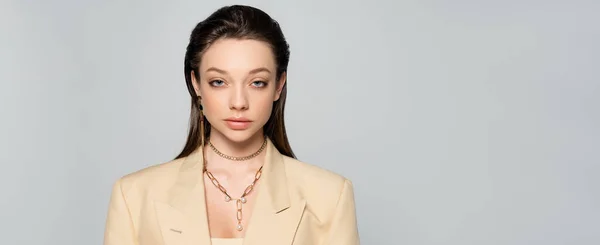 Pretty young woman in beige blazer looking at camera isolated on grey, banner — Photo de stock