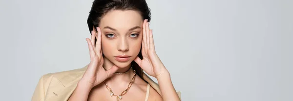 Young model in beige outfit looking at camera and posing isolated on grey, banner — Stockfoto