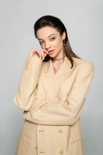 Pensive young woman in stylish outfit looking away while posing isolated on grey — Stock Photo