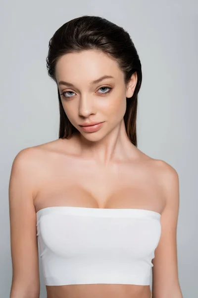 Портрет молодої жінки з макіяжем, який дивиться на камеру ізольовано на сірому — стокове фото