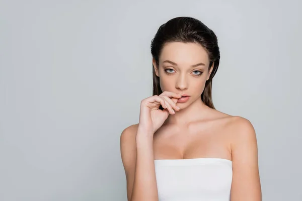 Portrait of sensual young woman with bare shoulders and makeup looking at camera isolated on grey — стоковое фото