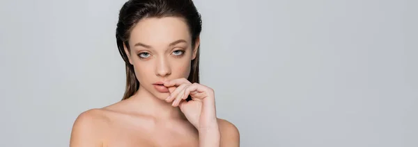 Portrait of young woman with bare shoulders and makeup looking at camera isolated on grey, banner — Stock Photo