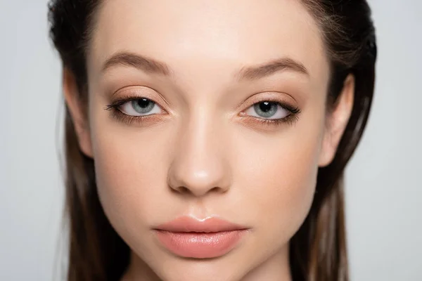 Close up view of young woman with blue eyes and makeup isolated on grey — Stock Photo