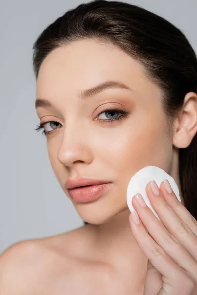 Close up of young woman removing makeup with soft cotton pad isolated on grey — Photo de stock