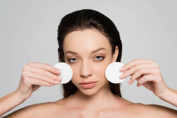 Young woman removing makeup with cotton pads isolated on grey — Stockfoto