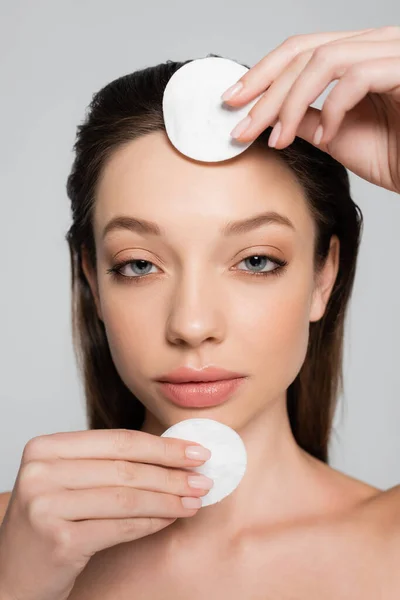 Close up view of young woman removing makeup with cotton pads isolated on grey — Stock Photo
