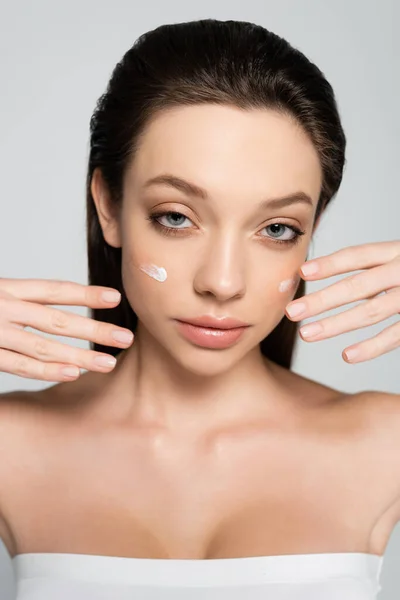 Young woman with bare shoulders and cream on cheeks gesturing isolated on grey — Photo de stock