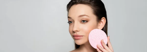 Young woman holding exfoliating sponge isolated on grey, banner — Stockfoto