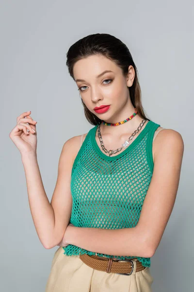 Young and stylish woman with red lips and necklaces posing isolated on grey - foto de stock