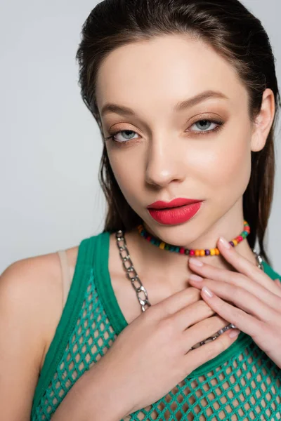 Young and stylish woman with red lips touching beads necklace while posing isolated on grey — Fotografia de Stock