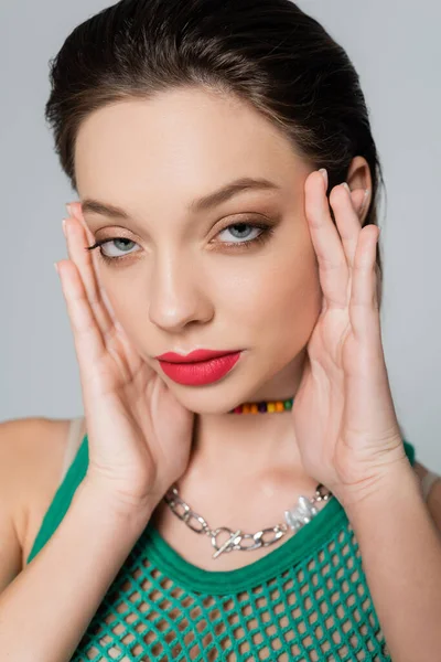 Close up of stylish woman with red lips looking at camera while posing isolated on grey — стоковое фото