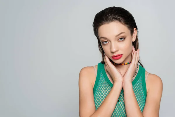 Trendy woman with red lips and colorful necklace posing isolated on grey — стоковое фото