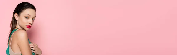 Young brunette woman with bright makeup posing while looking at camera on pink background, banner - foto de stock