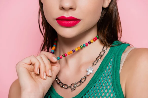 Cropped view of young model with bright makeup posing while pulling necklace isolated on pink — Fotografia de Stock