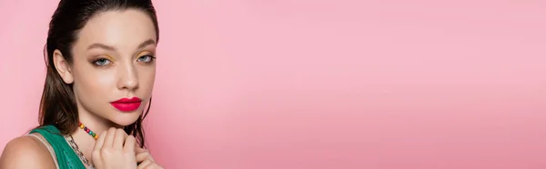Молода брюнетка модель з яскравим макіяжем дивиться на камеру ізольовано на рожевому, банер — стокове фото