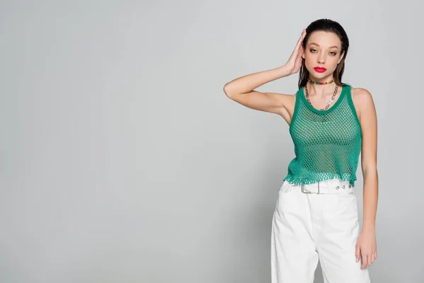 Young brunette woman in trendy outfit with bright makeup posing on grey — Fotografia de Stock