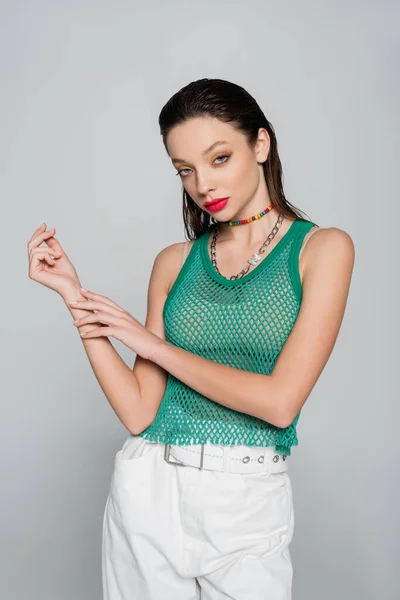 Trendy woman in green tank top and colorful necklace posing isolated on grey — Stock Photo