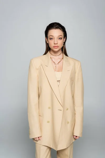 Brunette woman in stylish outfit with beige blazer posing isolated on grey — Foto stock