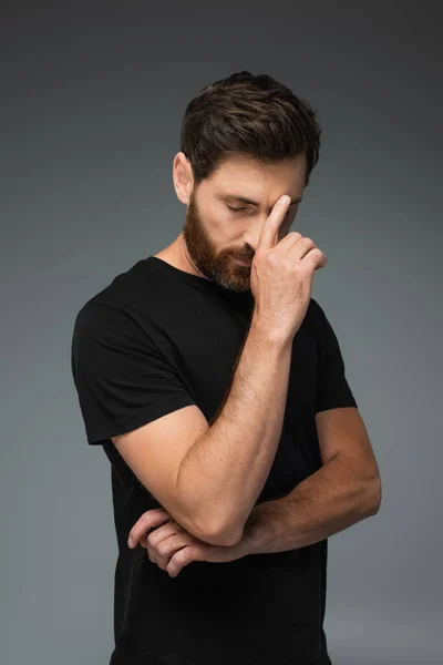 Portrait of thoughtful man in black t-shirt with closed eyes isolated on grey - foto de stock