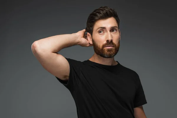 Portrait of puzzled man in black t-shirt looking away isolated on grey — Photo de stock