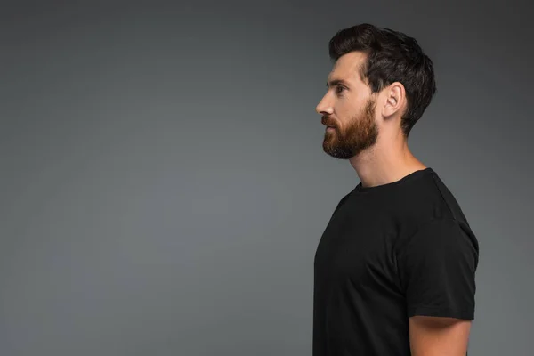 Вид сбоку босоногого мужчины в черной футболке, уединяющегося на сером — стоковое фото