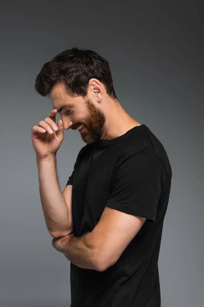 Side view of cheerful man in black t-shirt smiling isolated on grey — Stock Photo