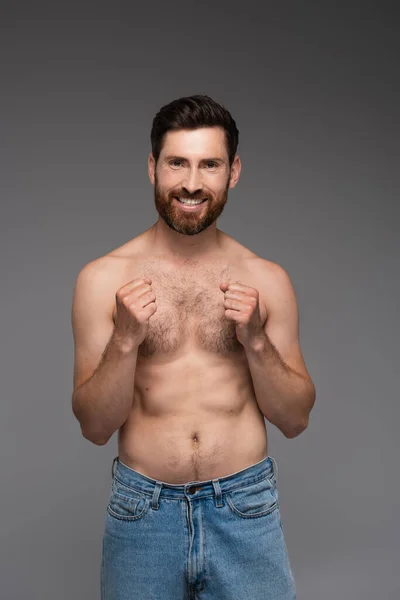 Shirtless and cheerful man with hair on chest smiling isolated on grey - foto de stock