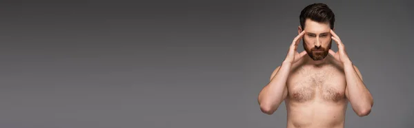 Shirtless and thoughtful man with beard touching temples isolated on grey, banner — Foto stock