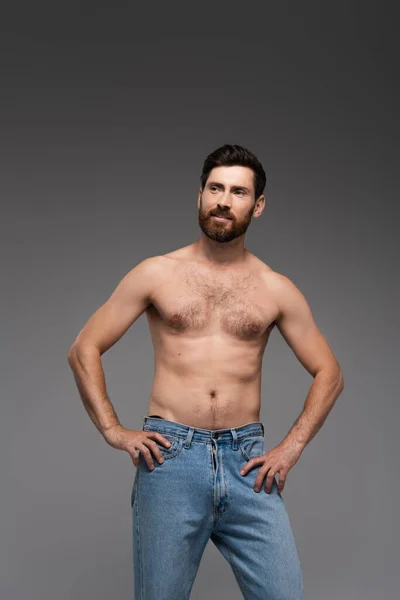 Shirtless man with beard posing in denim jeans and smiling isolated on grey — Foto stock