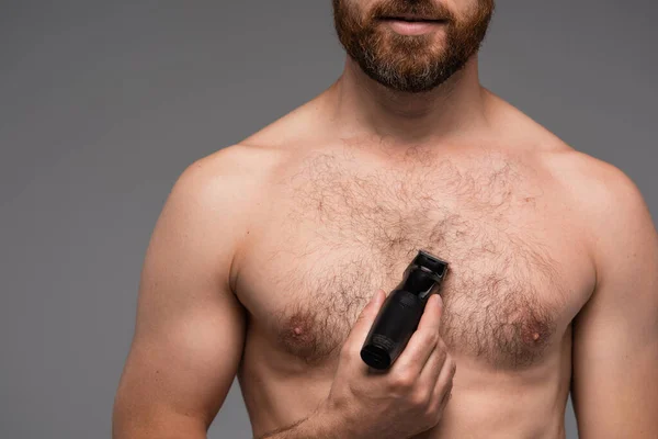 Cropped view of shirtless man shaving hair on chest with electric razor isolated on grey — Stock Photo