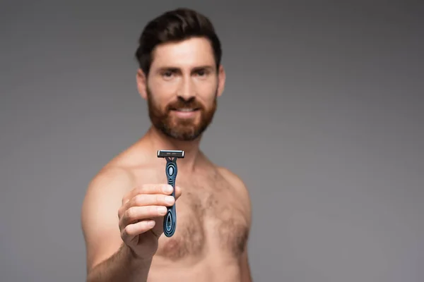 Blurred and shirtless man with beard holding safety razor isolated on grey — Foto stock