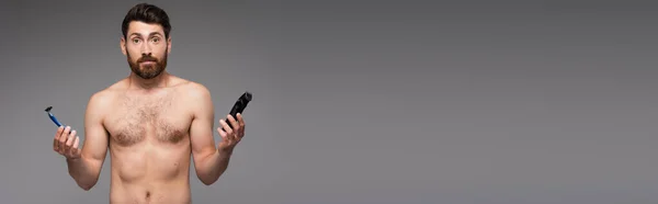 Confused and shirtless man with beard holding safety and electric razors isolated on grey, banner — Stock Photo