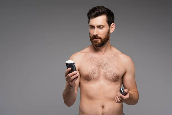 Мужчина без рубашки с бородой, держащий твердый дезодорант, изолированный на сером — стоковое фото
