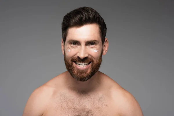 Cheerful and bearded man with cream on face smiling isolated on grey — Photo de stock