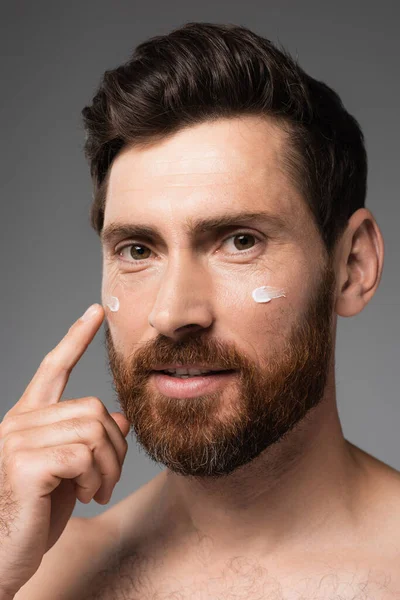 Close up of bearded man with cream on face smiling isolated on grey — Photo de stock