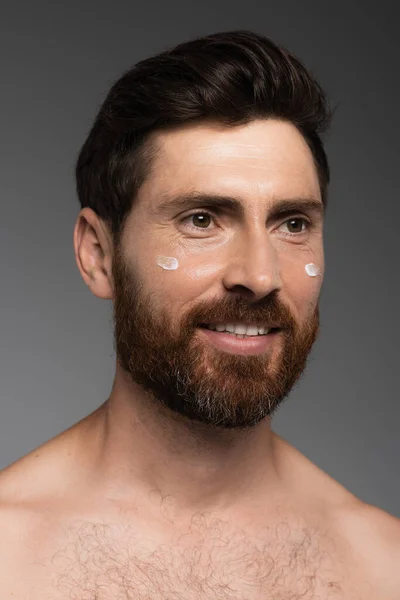 Portrait of bearded man with cream on face smiling isolated on grey — Stockfoto