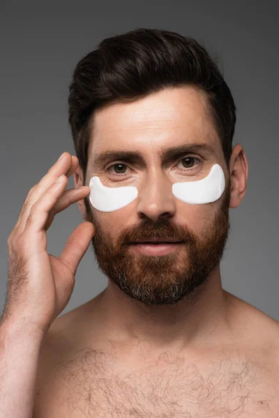 Portrait of bearded man with moisturizing eye patches isolated on grey — Fotografia de Stock