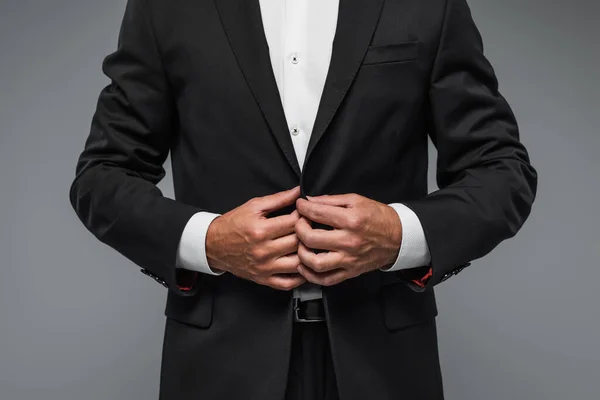 Cropped view of elegant man in black tuxedo adjusting blazer isolated on grey — Photo de stock