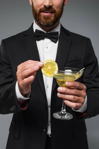 Cropped view of bearded man in suit holding glass with cocktail isolated on grey — Stock Photo