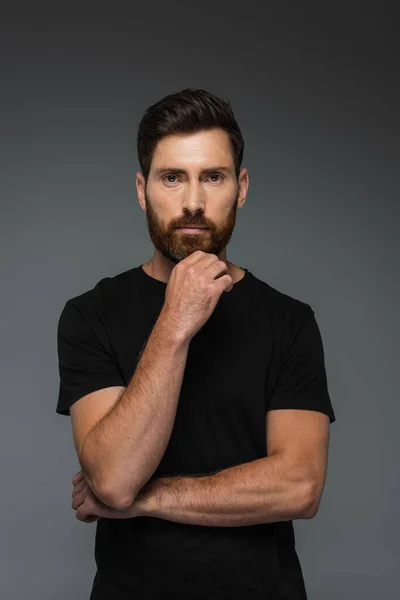 Portrait of thoughtful man in black t-shirt looking at camera isolated on grey — Stock Photo