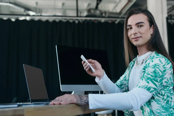 Queer designer using devices and smiling at camera in office — Foto stock