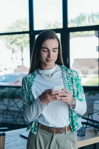 Brunette nonbinary designer using cellphone in creative agency — Fotografia de Stock